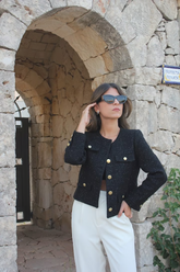 a lady wears a black tweed cropped jacket with white pants  and black sunglasses